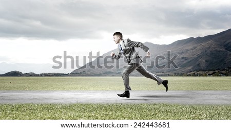 Young businessman in suit running on road