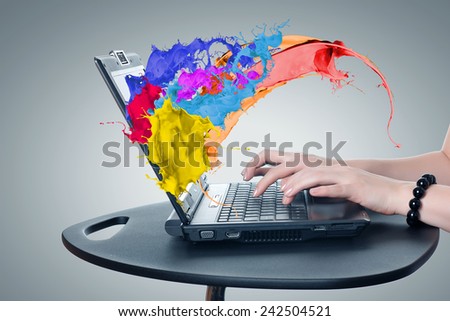 Hands of woman using laptop and colorful splashes on screen