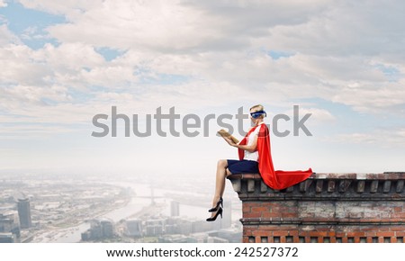 Young woman in super hero costume reading book