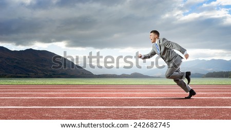 Young businessman in suit running on track