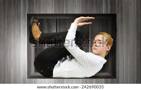 Young woman trapped in wooden cube in wall