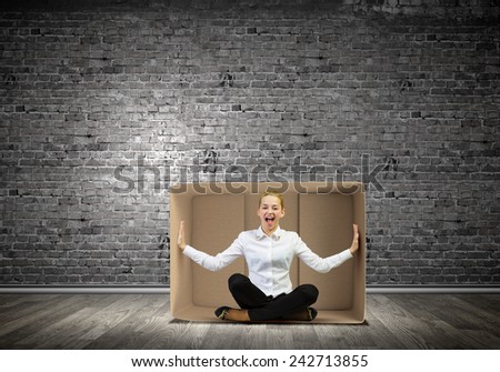 Young businesswoman sitting in carton box and feeling uncomfortable