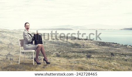 Young businesswoman sitting in chair against nature landscape