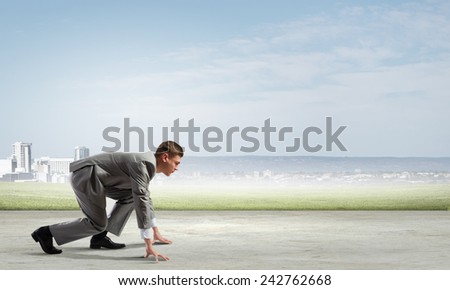 Side view of young businessman in start position ready to run