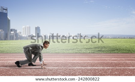 Side view of young businessman in start position on track