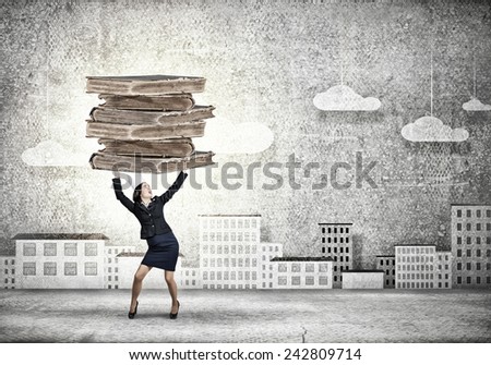 Young businesswoman in paper crown lifting books above head