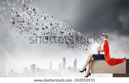Young woman in super hero costume reading book