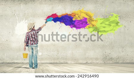 Boy of school age painting wall with brush