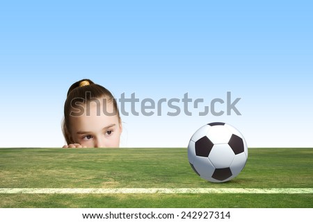 Little cute girl looking at soccer ball