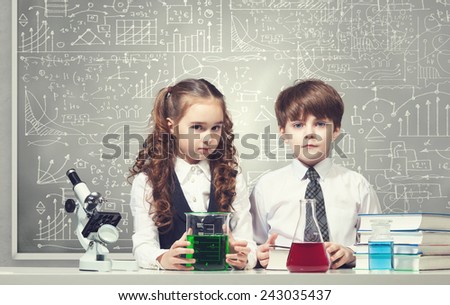 Cute girl and boy at chemistry lesson making tests