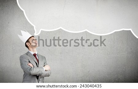 Young handsome businessman wearing white paper crown thinking something over