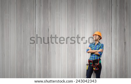 Attractive smiling woman engineer wearing helmet and tool belt