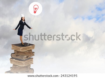 Young businesswoman in paper crown standing on pile of books