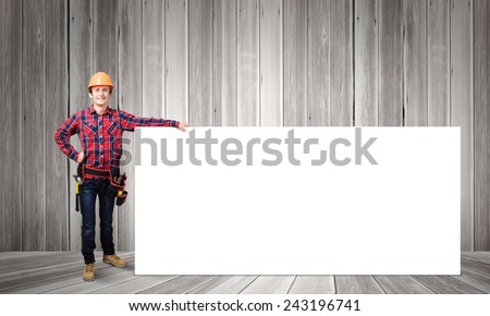 Young smiling craftsman holding with blank banner. Place for text