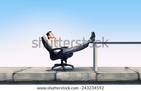 Young businessman sitting relaxed in chair with legs on table