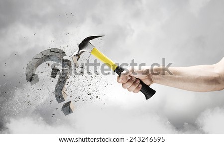 Close up of hammer in human hand breaking stone question mark