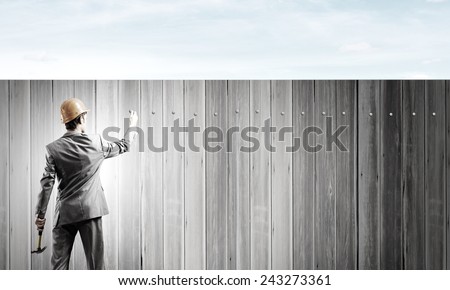 Rear view of businessman fixing white blank banner with hammer