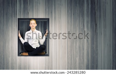 Young woman trapped in wooden cube in wall