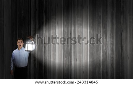 Young businessman walking with lantern in darkness
