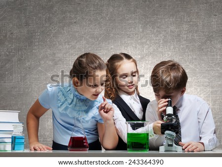 Three cute children at chemistry lesson making experiments