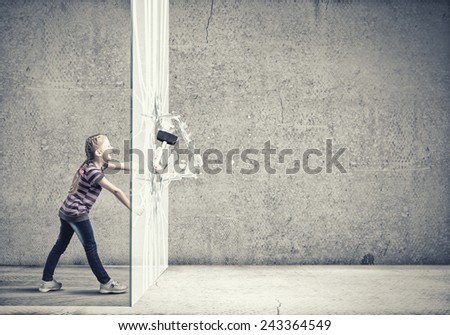 Cute little girl crushing cement wall with hammer