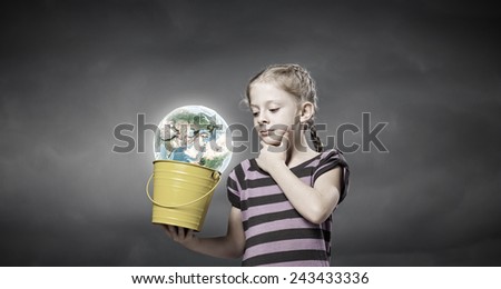 Cute girl looking at Earth planet in her bucket. Elements of this image are furnished by NASA