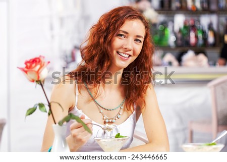 Portrait of young pretty woman sitting at cafe and eating dessert