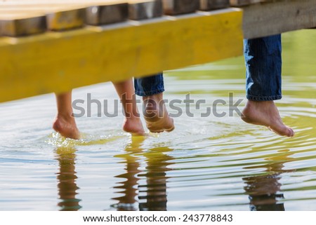 Close up of people's feet sitting on bridge