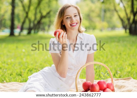 Young pretty woman in summer park with apple
