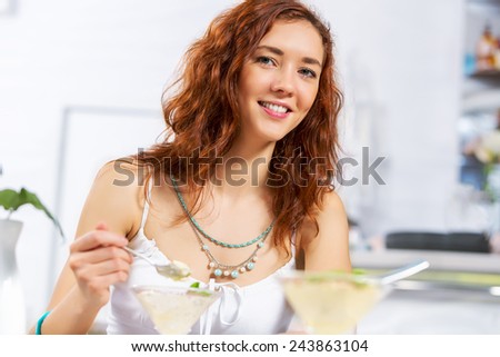 Portrait of young pretty woman sitting at cafe and eating dessert