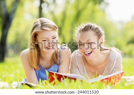 Young pretty girls in summer park reading book