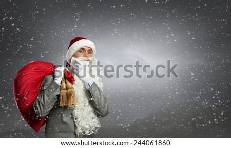 Businessman in Santa hat with red gift bag behind back