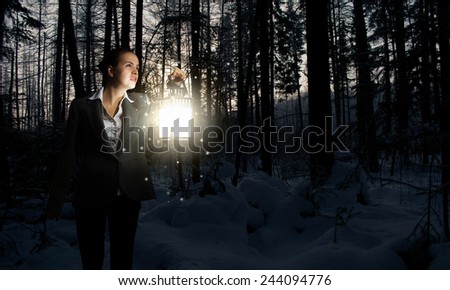 Young pretty businesswoman with lantern in darkness
