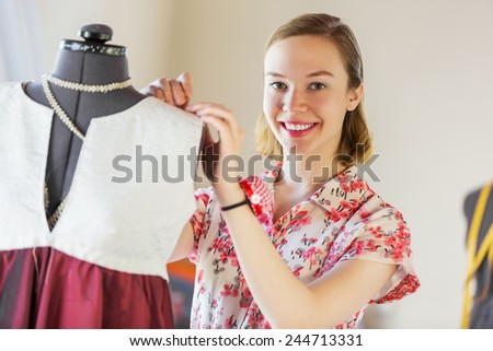 Pretty dressmaker at work pinning dress on dummy