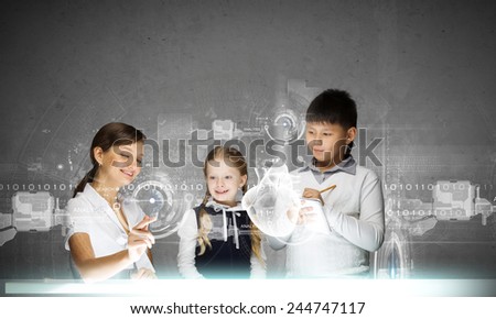 Young teacher and her pupils examining hologram of human heart