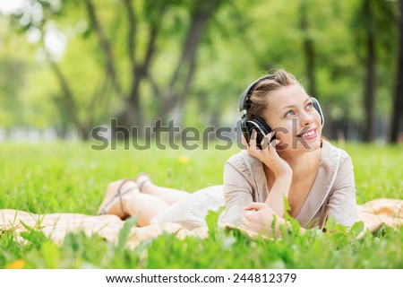 Young attractive girl in summer park wearing headphones