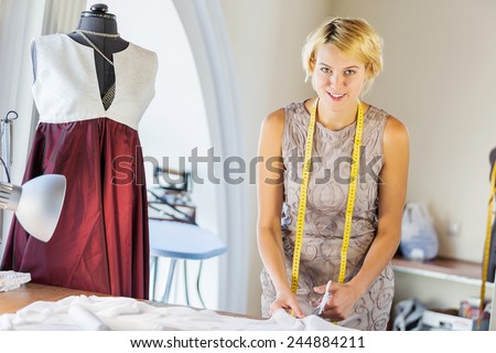 Pretty dressmaker at work pinning dress on dummy