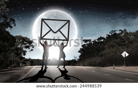 Silhouettes of young couple at night holding email sign