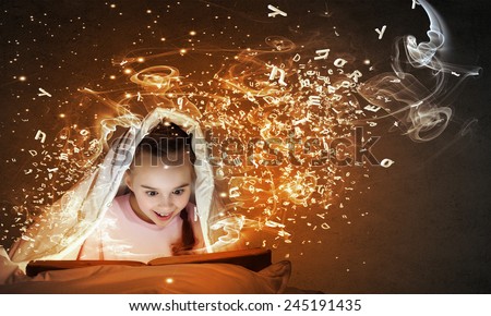 Cute girl in bed under blanket with book in hands