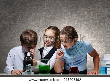 Three cute children at chemistry lesson making experiments