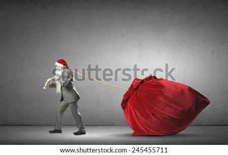 Businessman in Santa hat pulling big red bag