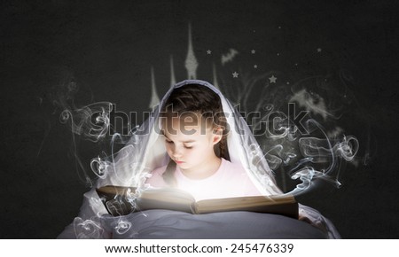 Cute girl in bed under blanket with book in hands