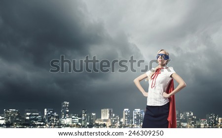 Young confident woman in red cape and mask