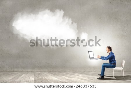 Young man sitting in chair and using laptop