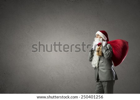 Businessman in Santa hat with red gift bag behind back