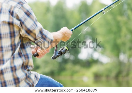 Close up of guy sitting on bridge and fishing