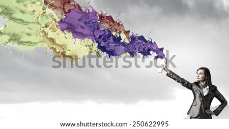Businesswoman spraying colorful paint splashes from container
