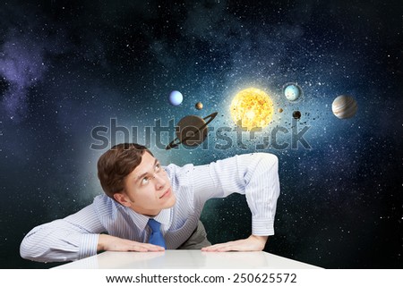 Young businessman leaning on table and planets of space spinning around