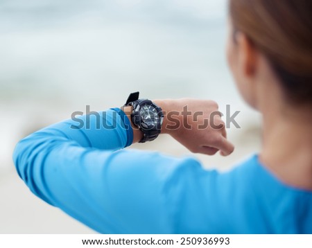 Sporty young woman looking at her watches