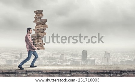 Young guy carrying pile of old books